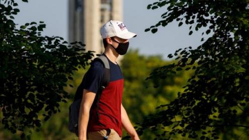 Student walking on campus wearing mask.
