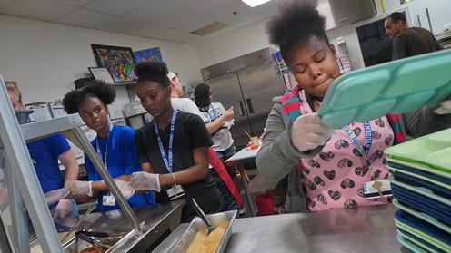 Image of young Black women working in an industrial kitchen.